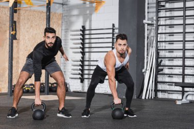 Çok ırklı sporcular spor salonunda çan çalıyorlar. 