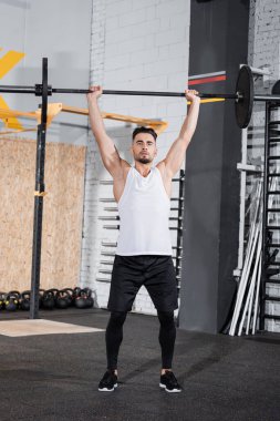 Sporcu spor merkezinde halter kaldırıyor. 