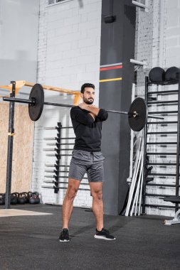 Genç Müslüman sporcu spor merkezinde halterle çalışıyor. 
