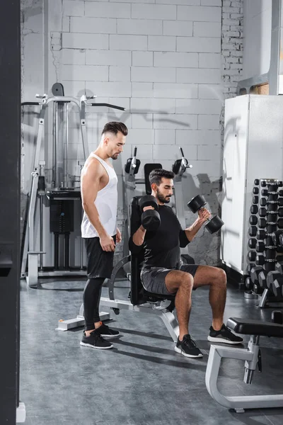 Jovem Treinador Perto Treinamento Desportista Árabe Com Halteres Ginásio — Fotografia de Stock