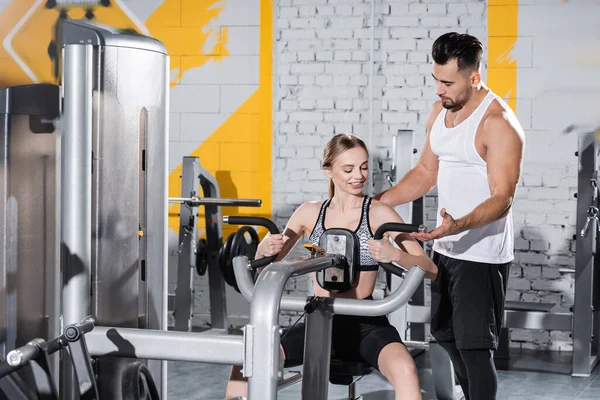 Entrenador Ayudando Deportista Rubia Entrenar Máquina Crunch Gimnasio — Foto de Stock