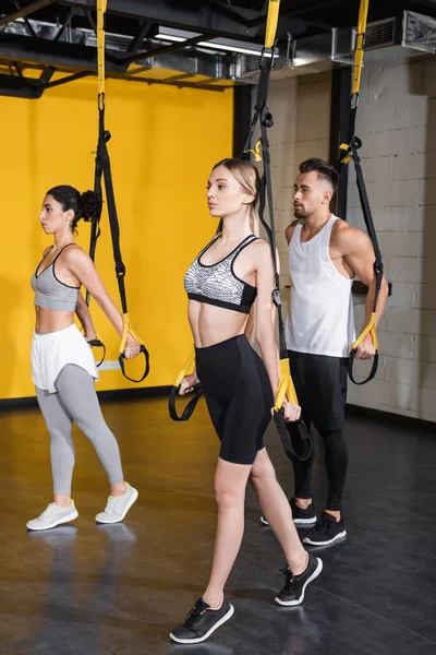 Joven Deportista Haciendo Ejercicio Con Correas Suspensión Cerca Amigos Multiétnicos —  Fotos de Stock