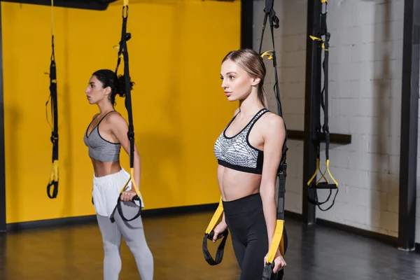 Mujer Rubia Entrenando Con Correas Suspensión Cerca Oriente Medio Amigo —  Fotos de Stock