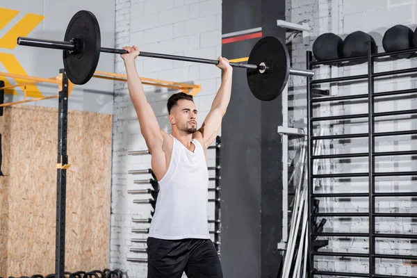 Sportsman holding barbell in sports center