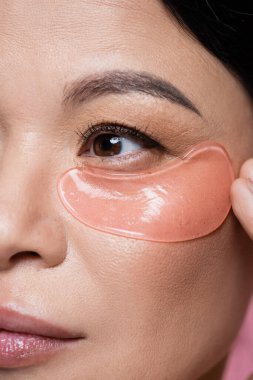 Pembe üzerine izole edilmiş göz bandı takan Asyalı kadının yakın görüntüsü 