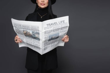 Fötr şapkalı şık bir kadının elinde koyu gri renkli bir seyahat gazetesi vardı.