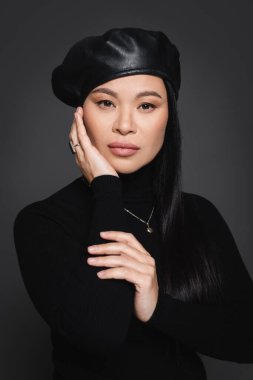Bere takmış zarif Asyalı model. Koyu gri renkli kameraya bakıyor.