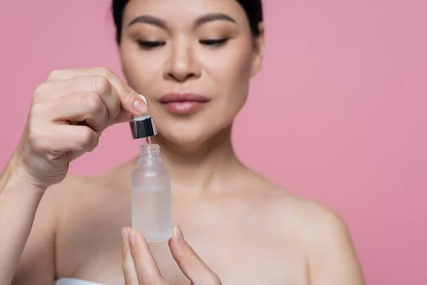 Бутылка Сыворотки Руках Размытой Азиатской Женщины Изолированной Розовом — стоковое фото