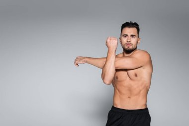 Genç sakallı ve kaslı sporcu griye ısınıyor.