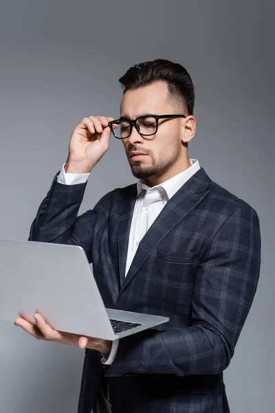 Businessman Suit Adjusting Glasses Looking Laptop Isolated Grey — Stock Photo, Image