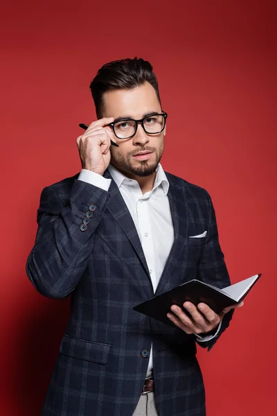 Szakállas Üzletember Kockás Öltönyben Szemüveget Igazít Miközben Tollat Jegyzetfüzetet Tart — Stock Fotó