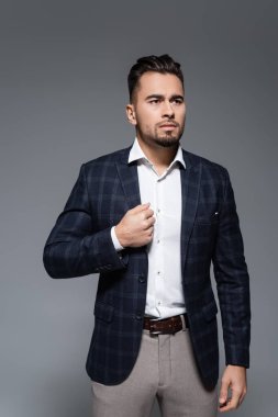 Sakallı iş adamı ekose ceketi gri renkte ayarlıyor.