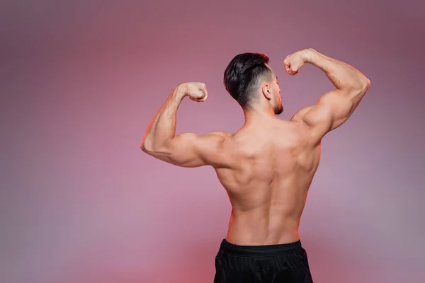 Visão Traseira Desportista Sem Camisa Mostrando Músculos Rosa Cinza — Fotografia de Stock