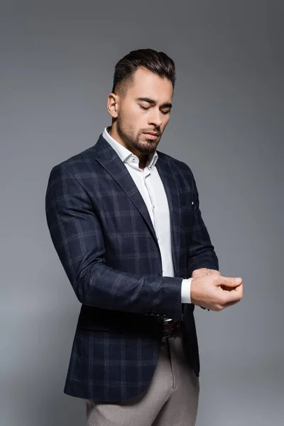 灰色で隔離された袖を調整する若い重大なビジネスマン — ストック写真
