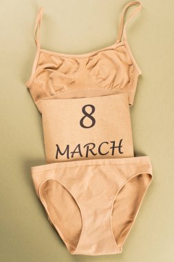 Top view of beige cotton underwear and card with 8 march lettering on green background  clipart