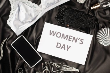 Sütyen, akıllı telefon ve siyah saten arka planda parfüm bulunan kadınlar günü harflerinin olduğu en iyi kart görüntüsü 