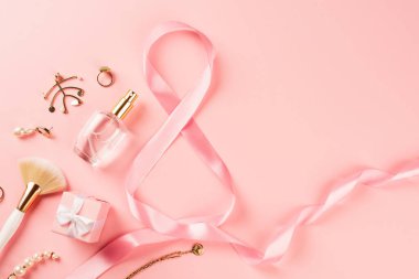 Pembe arka planda parfüm, aksesuar ve 8 şeklinde kurdele manzarası 