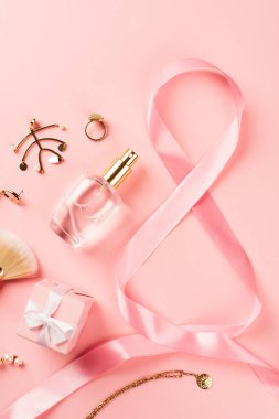 8 şeklinde kurdele, hediye, parfüm ve pembe arka planda aksesuarlar.