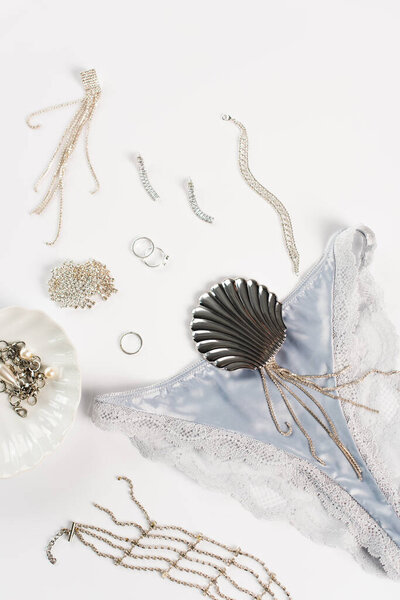 Top view of blue silk panties near accessories on white background 