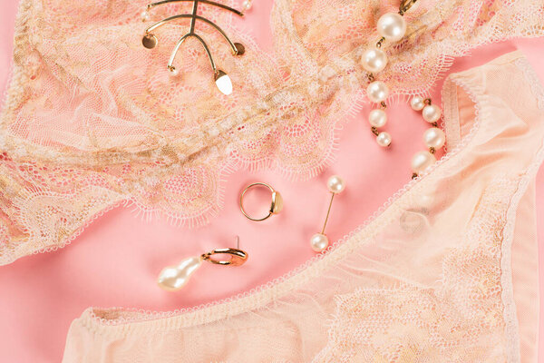 Top view of accessories near lace lingerie on pink background 
