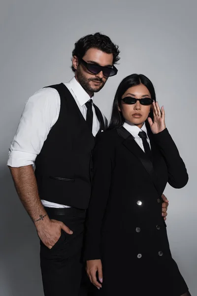 Resmi Giyinmiş Siyah Güneş Gözlüklü Zarif Bir Çift Gri Arka — Stok fotoğraf