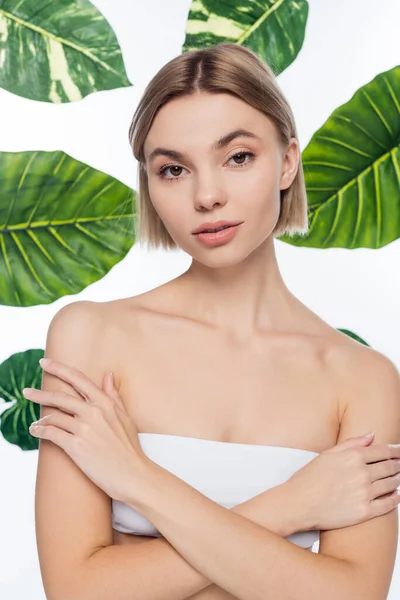 白い熱帯緑の葉の近くに裸の肩を持つ若い女性 — ストック写真