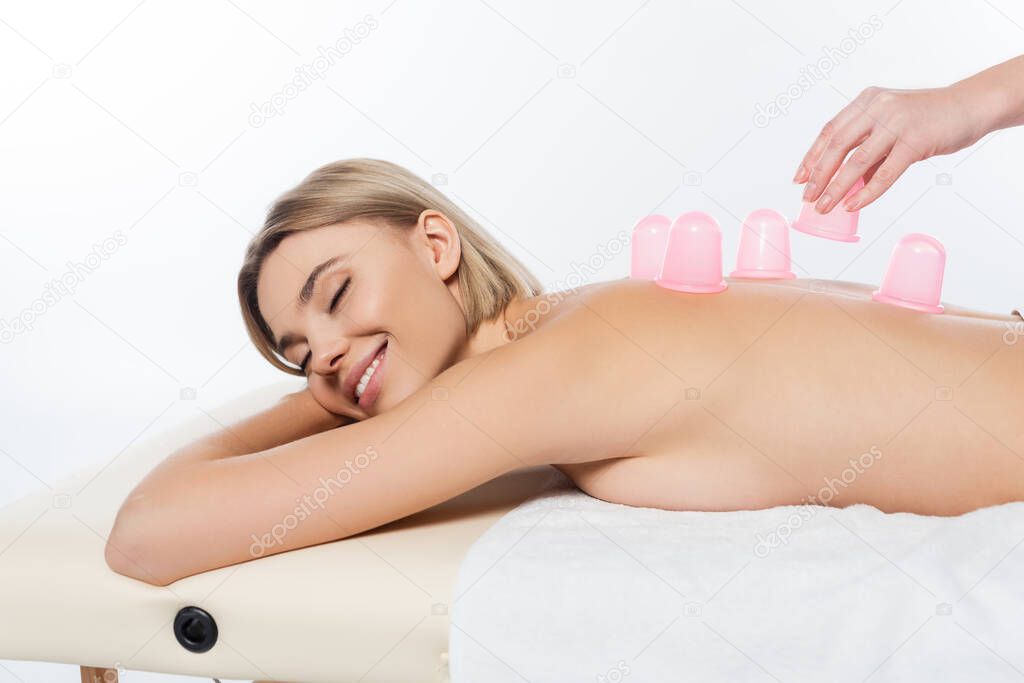 masseuse putting pink massage cups on back of cheerful client on white