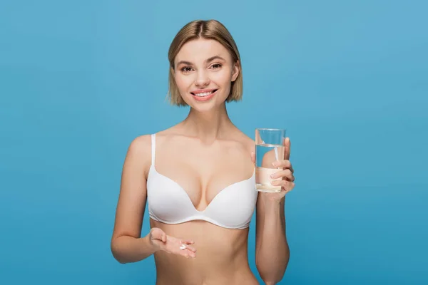 Uśmiechnięta Młoda Kobieta Białym Staniku Trzymająca Kapsułki Szklankę Wody Odizolowanej — Zdjęcie stockowe