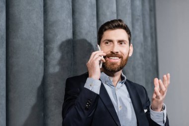 Resmi olarak gülümseyen adam otel lobisinde akıllı telefondan konuşuyor. 