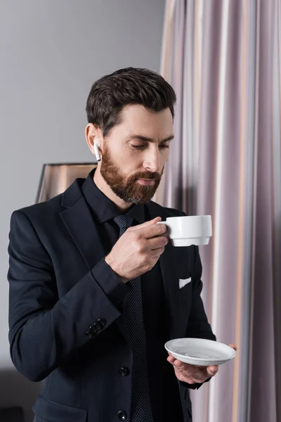 Bearded Businessman Earphone Holding Cup Saucer Hotel Room — Stock Photo, Image
