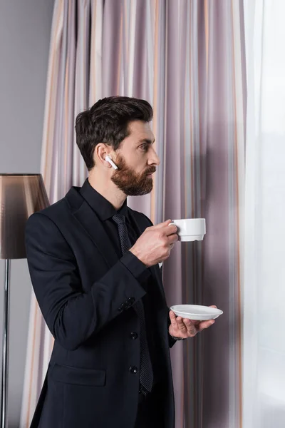 Zijaanzicht Van Man Met Baard Oortelefoon Met Schotel Beker Hotelkamer — Stockfoto