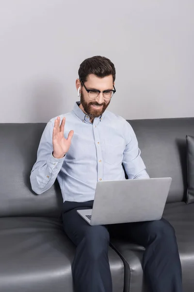 Hombre Feliz Anteojos Saludando Mano Mientras Utiliza Ordenador Portátil Hotel — Foto de Stock