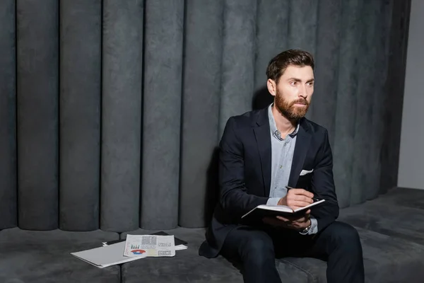 Bearded Businessman Writing Notebook Infographics Hotel Foyer — Stock Photo, Image