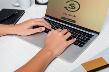 Bilgisayarda yazı yazan bir kadının beyaz masanın yanındaki kredi kartının yanında nakit para ile görüntüsü.