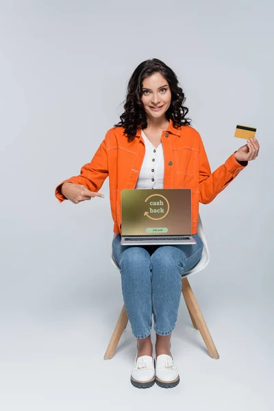 Vrolijke Jonge Vrouw Oranje Jas Wijzen Naar Laptop Met Cashback — Stockfoto