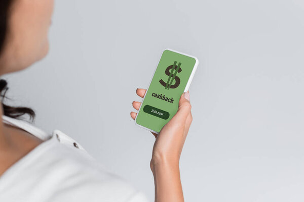 обрезанный вид размытой женщины, держащей мобильный телефон с возвратом денег и табличкой доллара на экране, изолированном на сером 