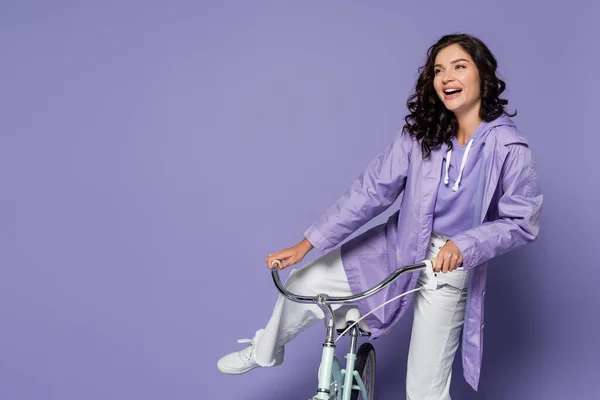 Jovem Alegre Capa Chuva Violeta Sentado Bicicleta Isolado Roxo — Fotografia de Stock