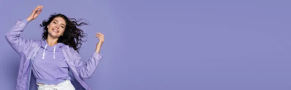 幸せな若い女性レインコートジェスチャーの孤立した紫のバナー — ストック写真