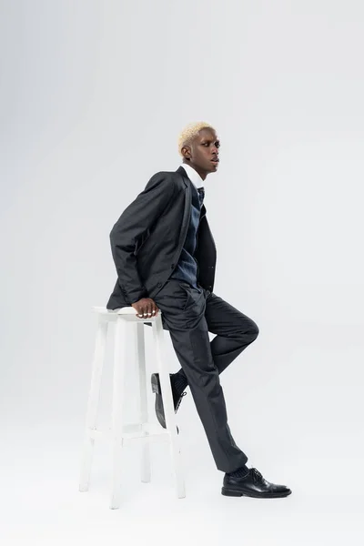 Повна Довжина Блондинки Афроамериканця Костюмі Спираючись Біле Крісло Сірий — стокове фото