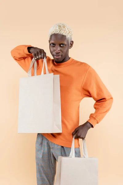 Jong Afrikaans Amerikaans Man Oranje Sweater Houden Boodschappentassen Geïsoleerd Beige — Stockfoto