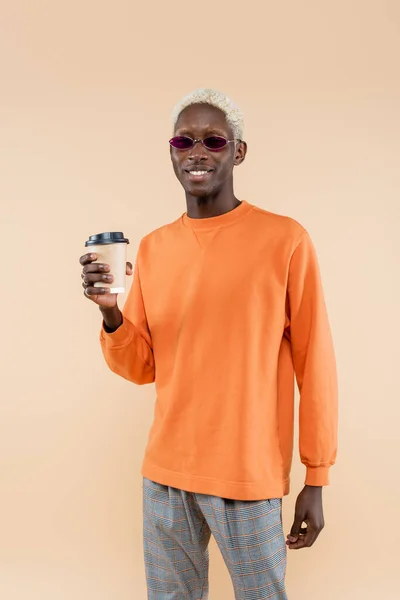 ベージュで隔絶されたサングラス保持紙コップで陽気なアフリカ系アメリカ人男性 — ストック写真