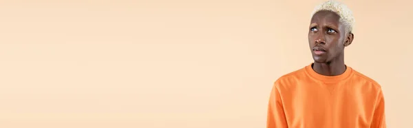 Álmodozó Afro Amerikai Férfi Narancssárga Pulóverben Elzárva Bézsen Banneren — Stock Fotó