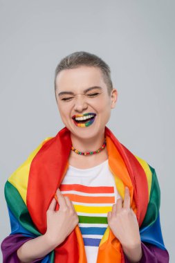 lgbt bayrağı ve gökkuşağı renginde dudakları olan mutlu bir kadın. Gri renkte gülüyor.