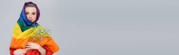 молодая женщина, завернутая в флаг lgbt, держа цыганские цветы изолированы на сером, баннер