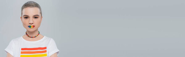 молодая женщина в радужных тонах футболка, смотрящая на камеру, изолированную на сером, баннер