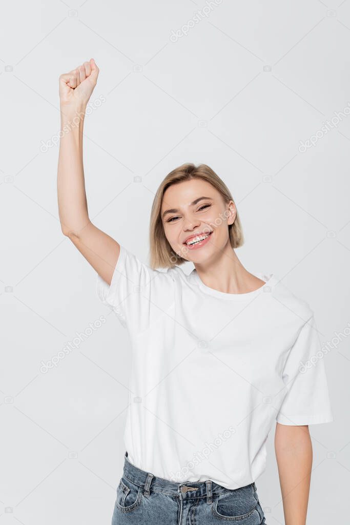 Happy blonde woman showing yes gesture isolated on grey, feminism concept