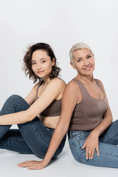 Las Mujeres Sonriendo Cámara Mientras Están Sentadas Sobre Fondo Gris — Foto de Stock