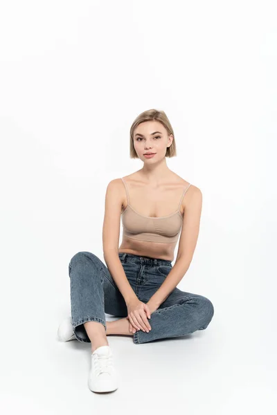 Mulher Loira Cima Jeans Sentados Fundo Cinza — Fotografia de Stock