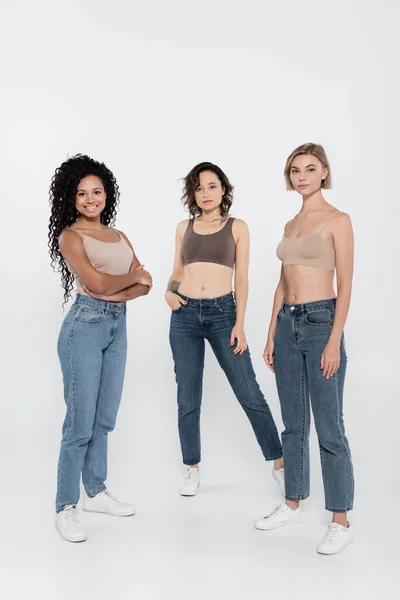 Mujeres Jóvenes Interracial Tops Jeans Posando Sobre Fondo Gris — Foto de Stock