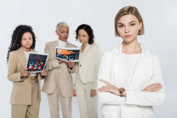 Blonde Businesswoman Looking Camera Blurred Interracial Colleagues Papers Isolated Grey — Stock Photo, Image